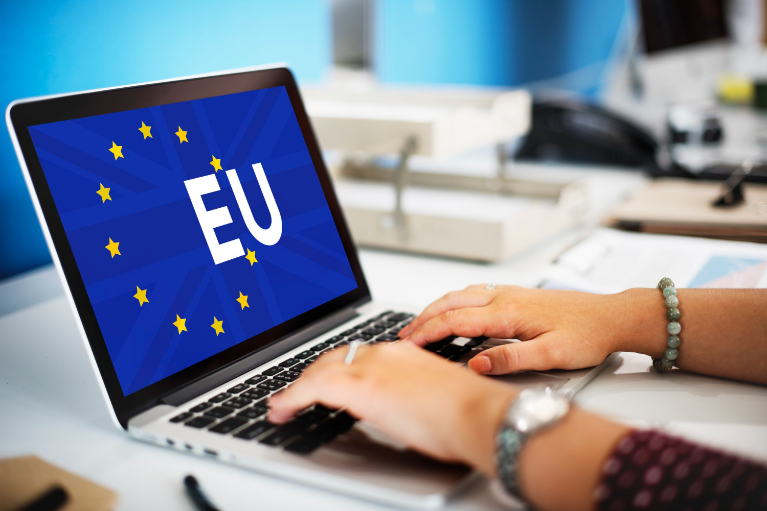 Person typing on laptop with EU flag in background representing GDPR compliance for website owners